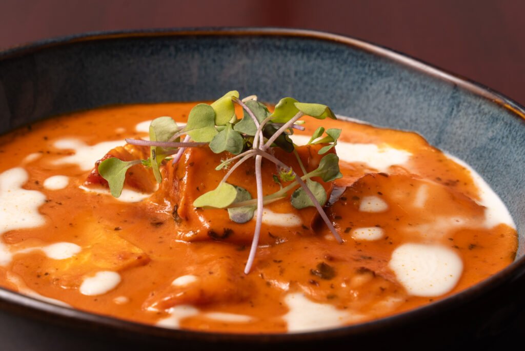 Chicken tikka masala in creamy tomato sauce, topped with cream and microgreens