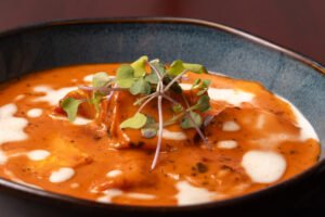 Chicken tikka masala in creamy tomato sauce, topped with cream and microgreens