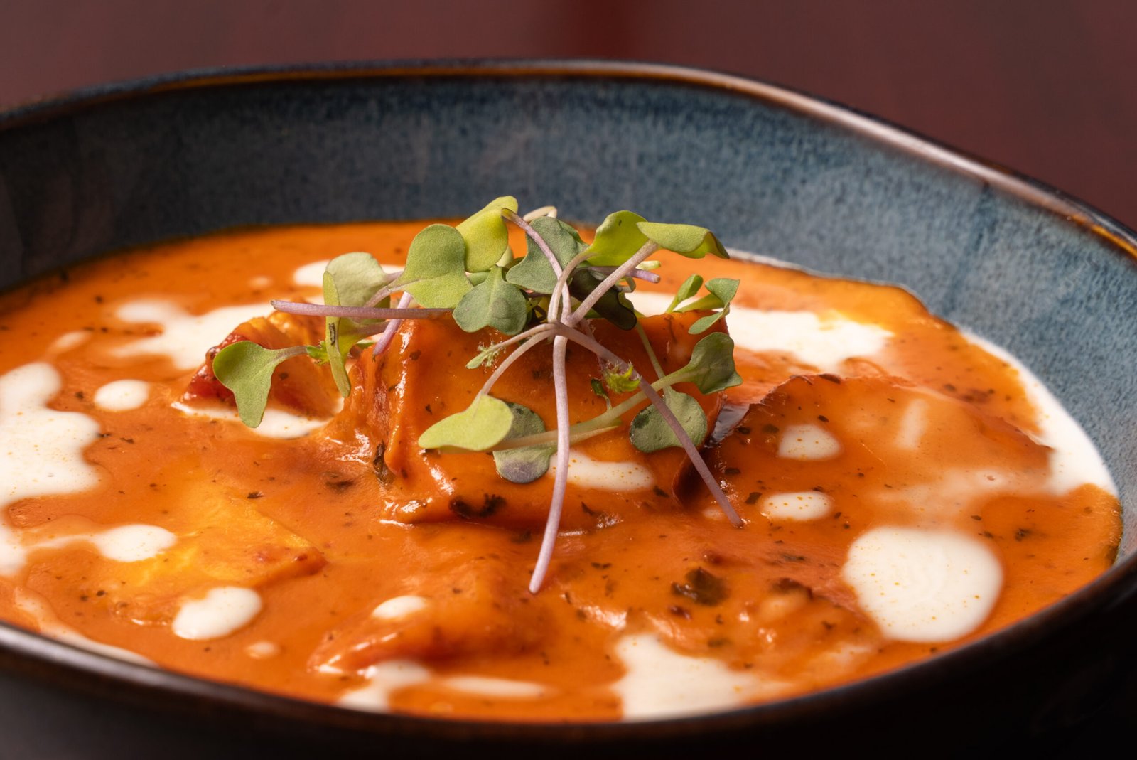 Chicken tikka masala in creamy tomato sauce, topped with cream and microgreens
